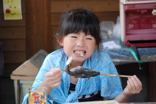 焼き魚を食べる子供